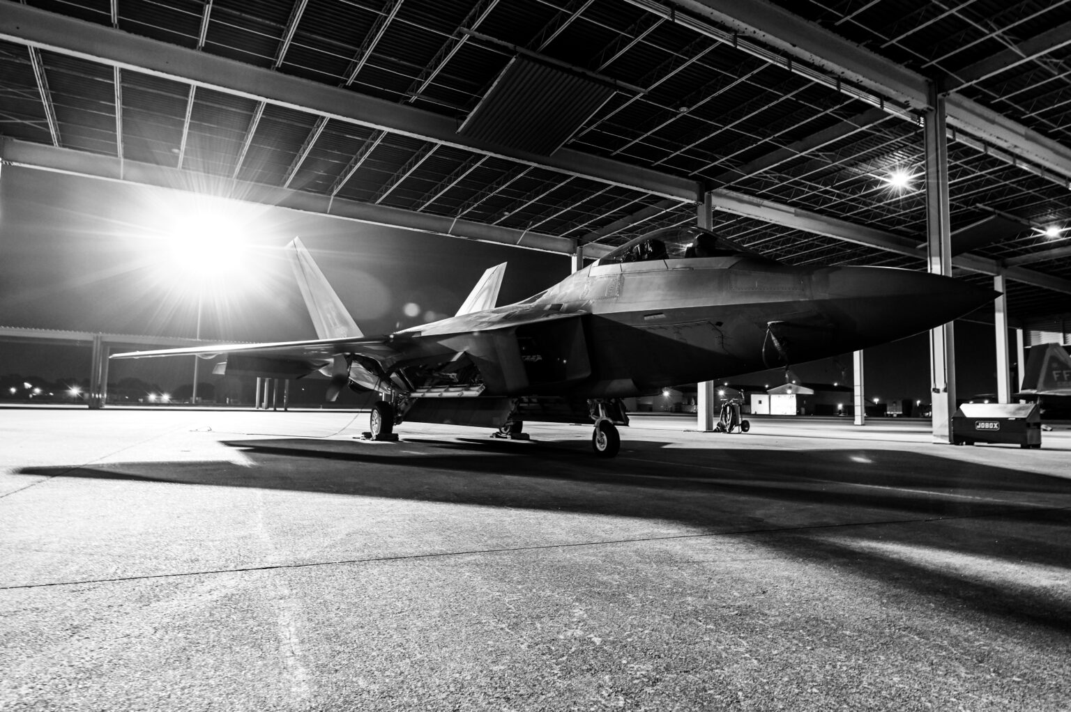 F-22 Raptor in hangar (grayscale).